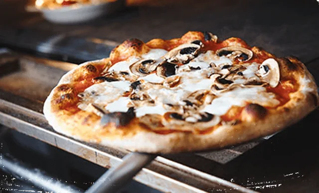 A pizza coming out of the oven at Casa Nirvana