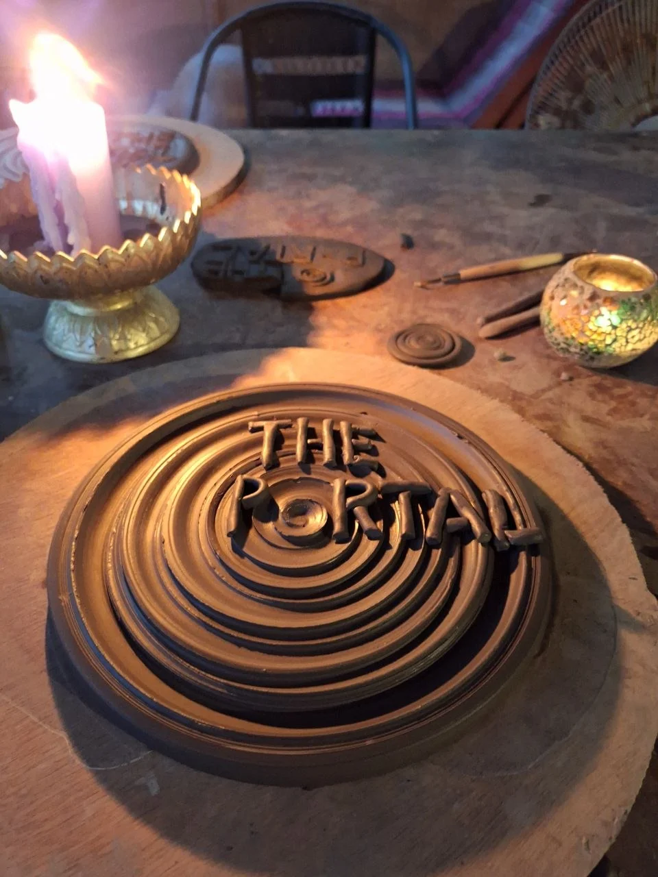 A clay piece with the words THE PORTAL, by candlelight