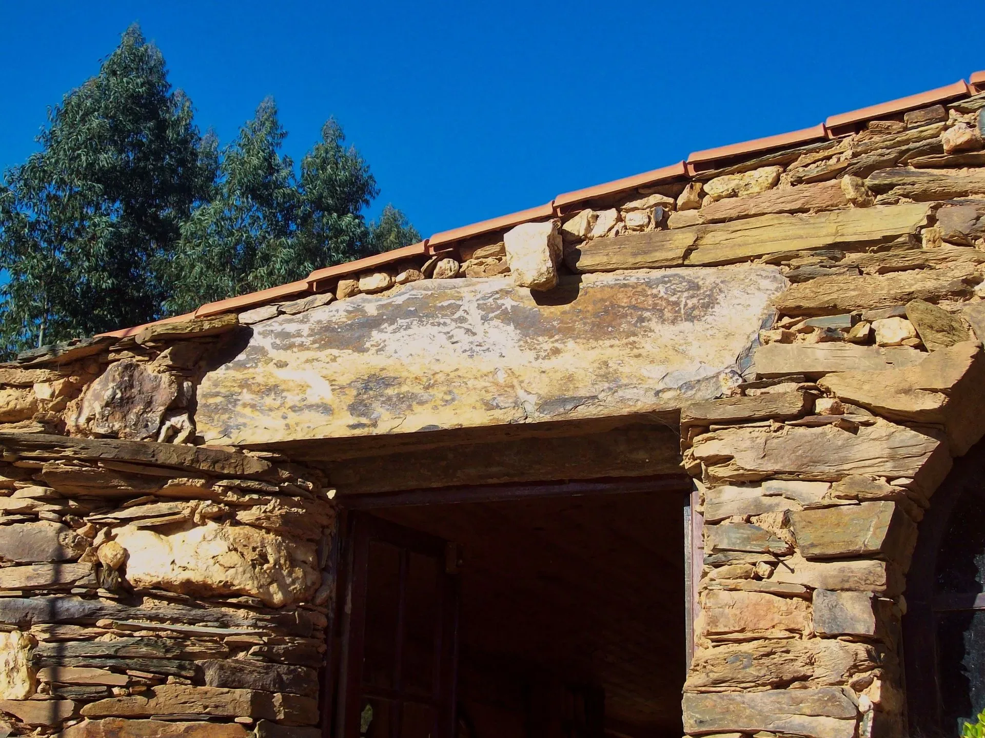 Schist gable and eaves against a deep blue sky