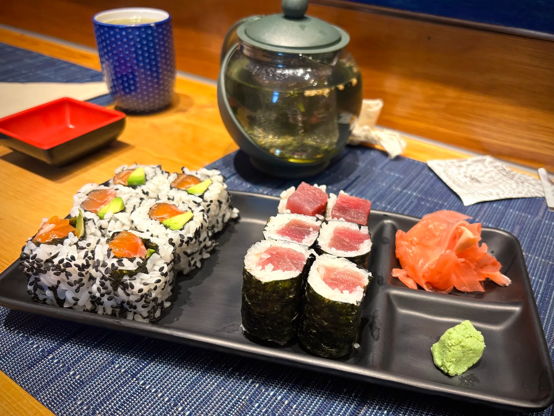 A plate of sushi rolls with ginger and wasabi at SAZANAMI